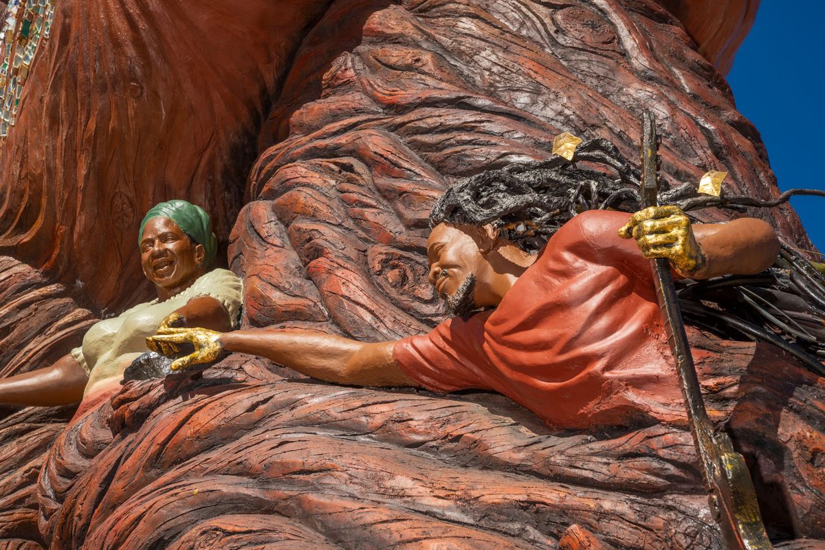 The smiling elder in a green head wrap and the musician reaching for her
